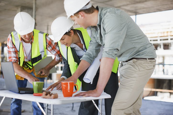Collaborateurs sur chantier étudiant un plan