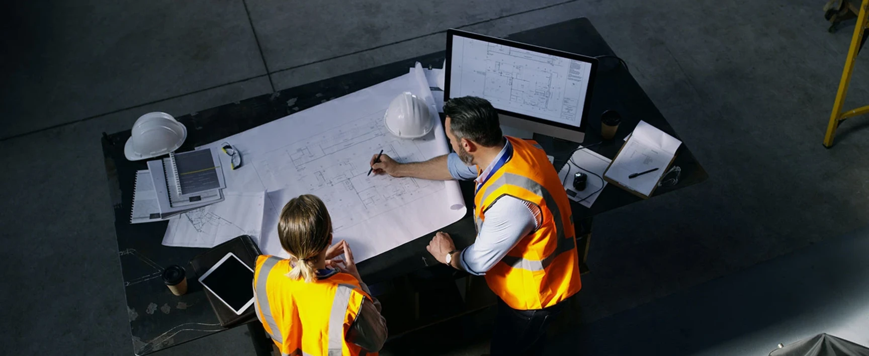 2 collaborateurs travaillent sur un plan de chantier de construction