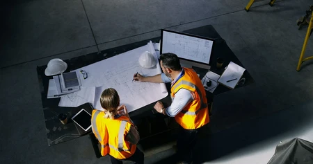 2 collaborateurs travaillent sur un plan de chantier de construction